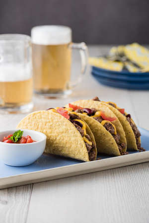 Beef tacos with salsa,cheddar cheese, tomato, beans and beerの写真素材