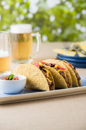 Mexican tacos with beef, cheddar cheese, tomato, beans and salsa dips at beer gardenの写真素材