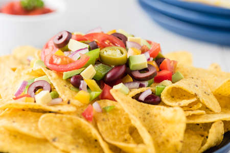 Vegetarian nachos tomato, beans, capsicum, avocado, olive, jalapeno and dipping saucesの写真素材