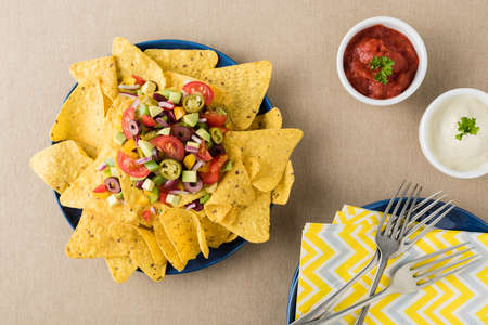 Vegetarian nachos tomato, beans, capsicum, avocado, olive, jalapeno and dipping saucesの写真素材