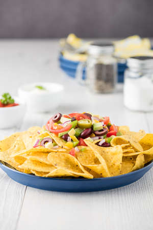 Vegetarian nachos tomato, beans, capsicum, avocado, olive, jalapeno and dipping saucesの写真素材