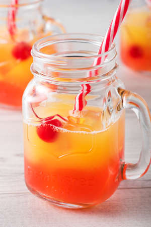 Tequila sunrise cocktails in glass jar with garnishの写真素材