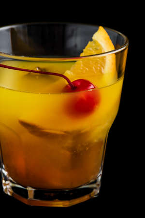 Mai Tai cocktail with orange and maraschino cherry garnish on black backgroundの写真素材