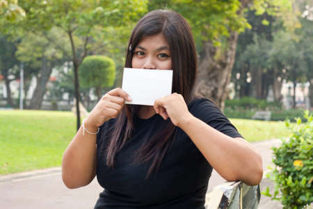 Women sitting in the park and hold a white card.
