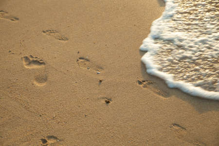 Footprints on the sand. The waves hitting the shore. Media and holidays.の写真素材
