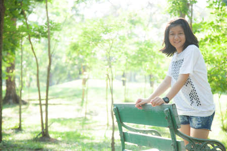 Woman standing on a stool. In the park with trees and greenery.の写真素材