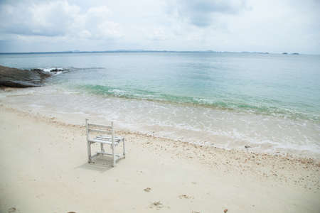 White wooden chair. Placed on the sand beach by the sea.の写真素材