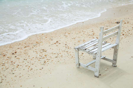 White wooden chair. Placed on the sand beach by the sea.