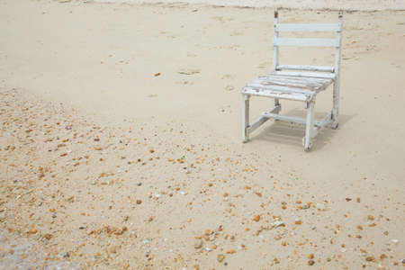 White wooden chair. Placed on the sand beach by the sea.の写真素材