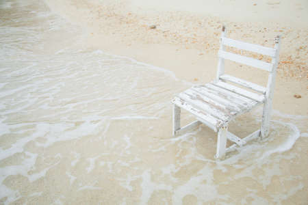 White wooden chair. Placed on the sand beach by the sea.の写真素材