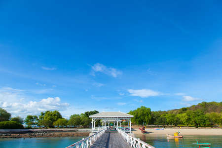 Wooden bridge stretching into the sea. Small boats moored nearby.の写真素材