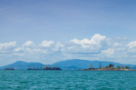 cargo ship Moored near the island behind a mountain.の写真素材