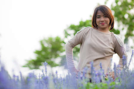 Portrait Asian woman standing. Flowers arranged in lotus-shape area in the park