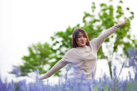 Portrait Asian woman standing. Flowers arranged in lotus-shape area in the park.she is relax.