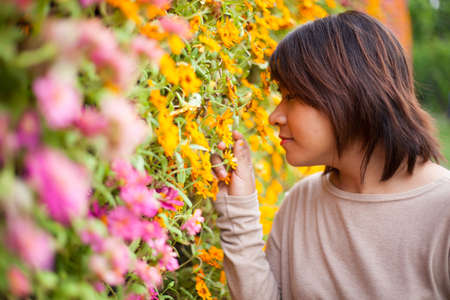 Portrait Asian woman standing near yellow flowers. And smell the flowersの写真素材