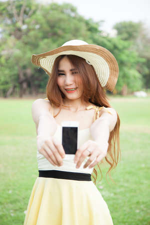 Asian woman smiling and handing a mobile phone.Smiling happy and Relax.の写真素材