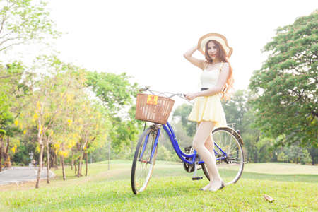 asian woman hold bicycle on the lawn. Trees in the parkの写真素材