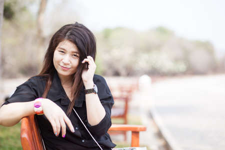 Asian women sitting on a bench. Black shirt sitting in the park.の写真素材