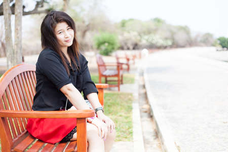Asian women sitting on a bench. Black shirt sitting in the park.の写真素材