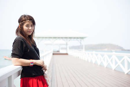 Asian women black shirt Standing on the wooden terrace of white beach.の写真素材