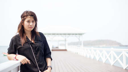 Asian women black shirt Standing on the wooden terrace of white beach.の写真素材