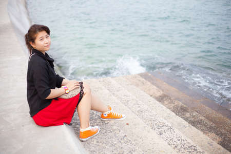 Asian women black shirt. Sitting on the pavement. Forward into the sea with the tide toward the...