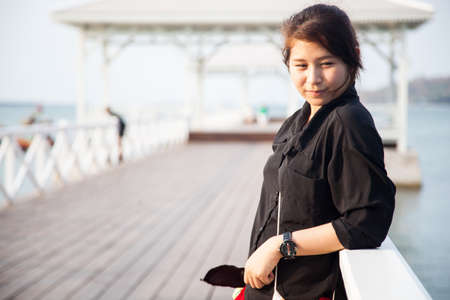 Asian women black shirt Standing on the wooden terrace of white beach.