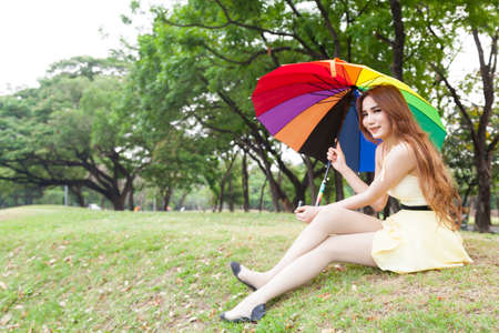 Woman with umbrella and sitting on the lawn. At the parkの写真素材