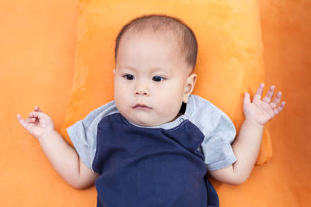 Baby boy.child Asian., And is lying on the orange sofaの写真素材