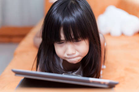 Girl playing with tablet. girl with long black hair.の写真素材