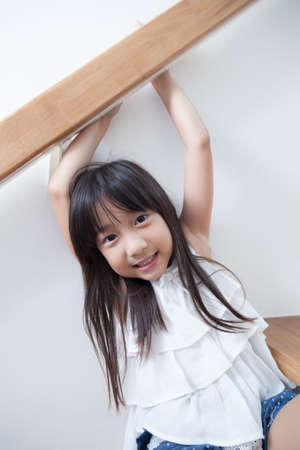 Child girl sitting on the ladder. And smiling happily.の写真素材