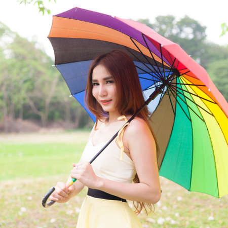 Woman holding multicolored umbrella On the grass in the park.の写真素材