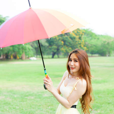 Woman with umbrella standing on the lawn. In the park during the day, the sun is strongest.の写真素材