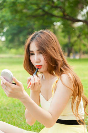 Woman in makeup Are lipstick and sitting on the lawn.の写真素材