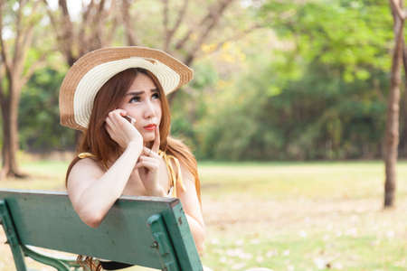 Woman talking on the phone Sitting on a bench in the park.の写真素材