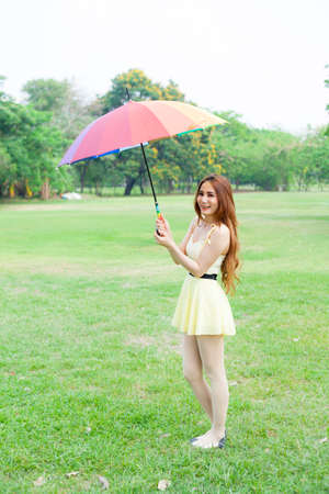 Woman with umbrella standing on the lawn. In the park during the day, the sun is strongest.の写真素材