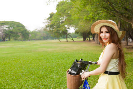 Woman riding a bicycle. Woman with hat riding a bicycle in the park.の写真素材