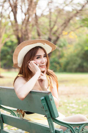 Woman talking on the phone Sitting on a bench in the park.の写真素材