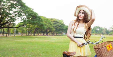 Woman with bike on the lawn. In the park on the lawn. With shady trees and naturalの写真素材