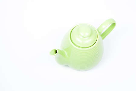 Green teapot on a white background with a single in the studio.