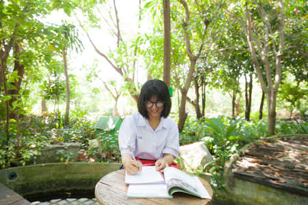 Girl reading and homework. At a table in the park There are some shady trees planted