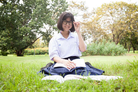 Schoolgirl was reading on the lawn. Smiling and happy within the park.の写真素材
