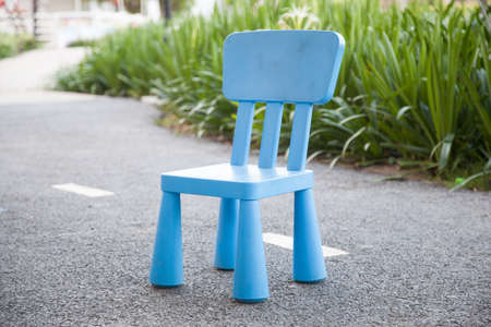 Blue plastic chair Location on the floor and walk in the park. Behind the bushesの写真素材