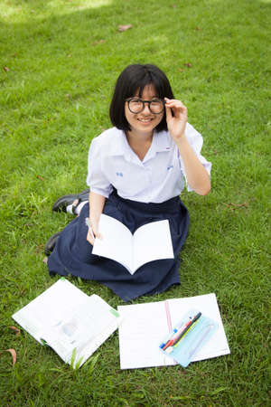 Schoolgirl was reading and homework on the grass in the park a happy.