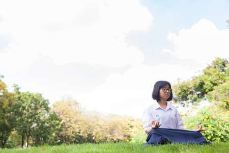 Schoolgirl are meditating. The grass in the park. Weather cloudy and clear sky.の写真素材