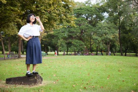 Girl standing on log. Smiling, happy and fun in the park.の写真素材