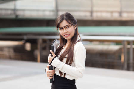 Happy asian businesswoman hold paper and document file.smile and stand on sidewalk.