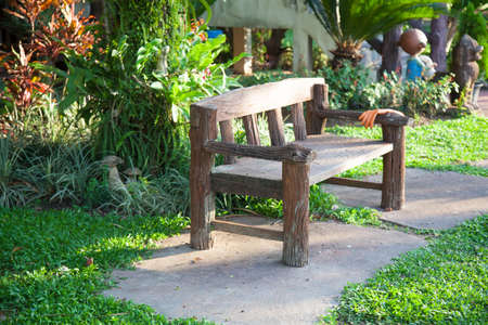 Benches on the walkway in the park on the grass. Decorated with trees and shrubs in the garden.