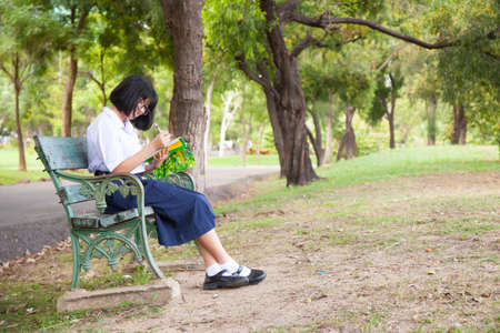 Girl sitting and reading a book. Sit on a bench in the park.の写真素材
