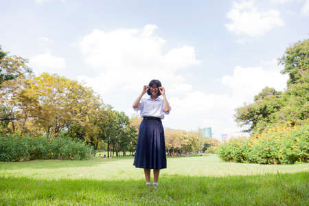 Schoolgirl standing on the lawn. Park in the Republic Laos a clear day. Clouds covered the skyの写真素材